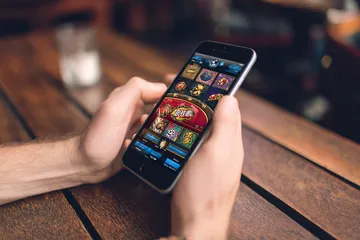 উৎসবের মুহূর্তে ঐতিহ্যবাহী পোশাক পরা এক আনন্দিত নারী তার স্মার্টফোন ব্যবহার করছেন, যা দেখায় 4777BIT অ্যাপ কীভাবে দৈনন্দিন জীবনের সঙ্গে সহজে মানিয়ে যায়।